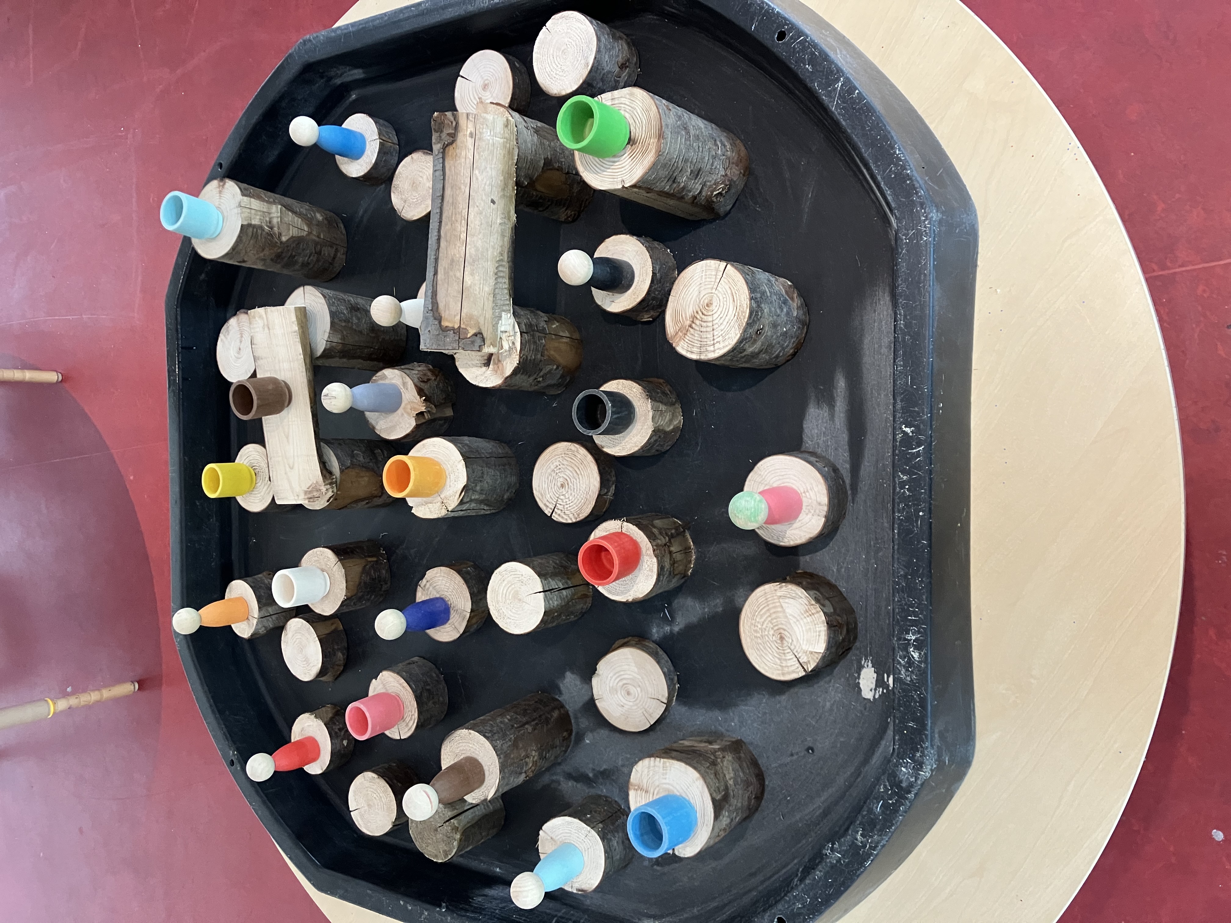 Loose parts play with wooden logs and coloured pegs at Greenbank Preschool
